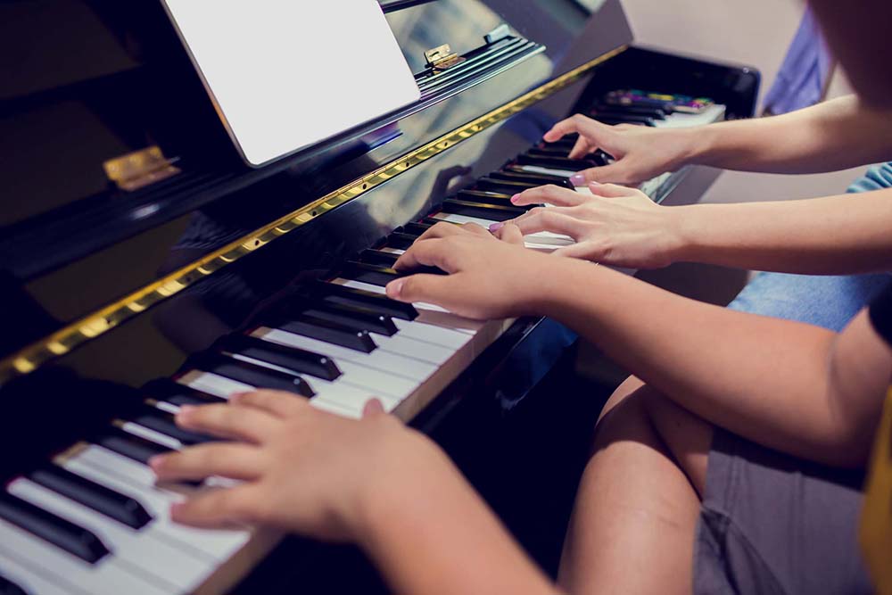 Two people playing on a piano