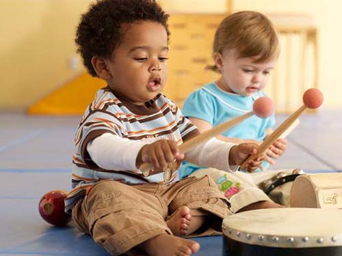 Two toddler boys playing musical instruments.
