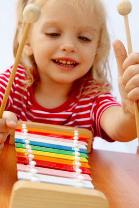 Small girl playing on a xylophone.